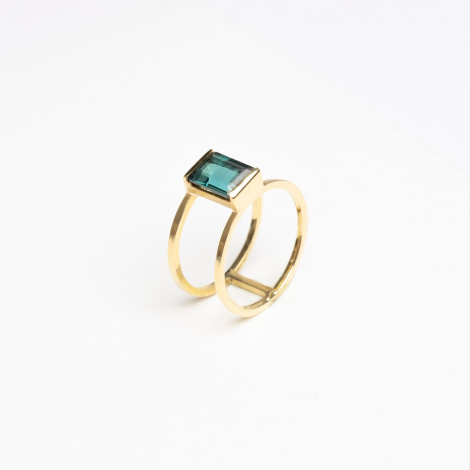 Gold ring with a green gemstone on a white background