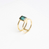 Gold ring with a green gemstone on a white background